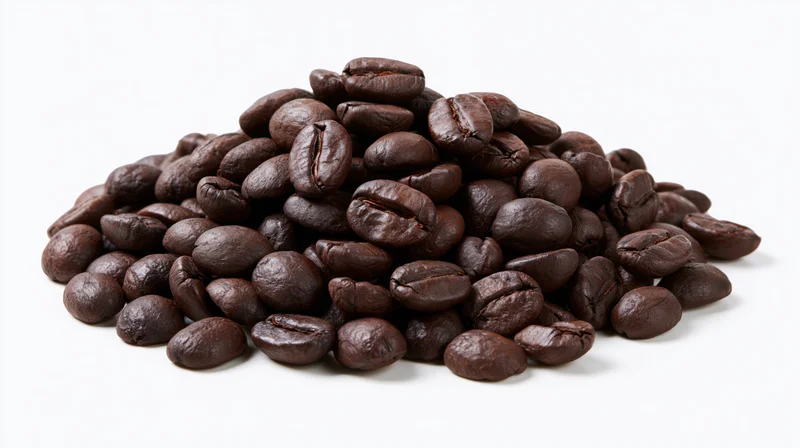 Small loose pile of dark roasted coffee beans heaped together on white background