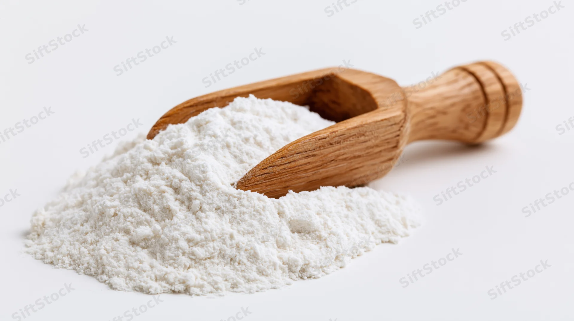 Wooden scoop resting on a mound of fine white flour against a plain white background