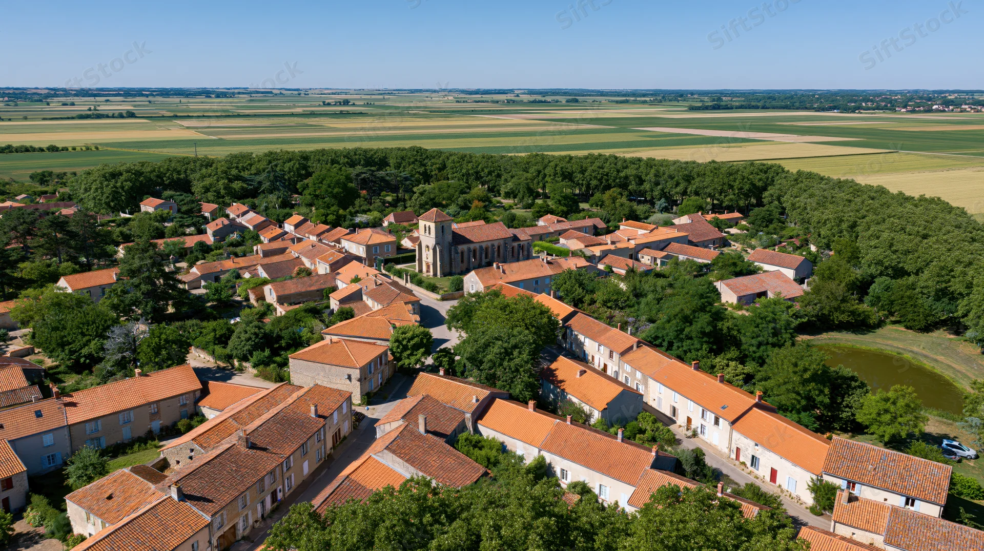 Aerial view of a small french village with terracotta rooftops and surrounding farmland