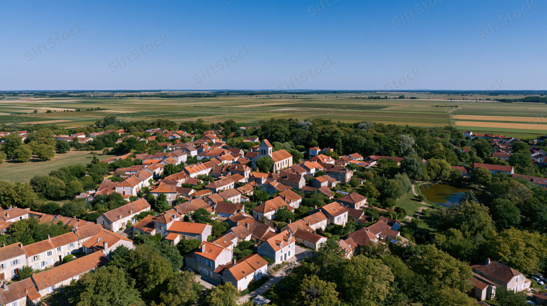Aerial view of a small french village with terracotta rooftops and surrounding farmland
