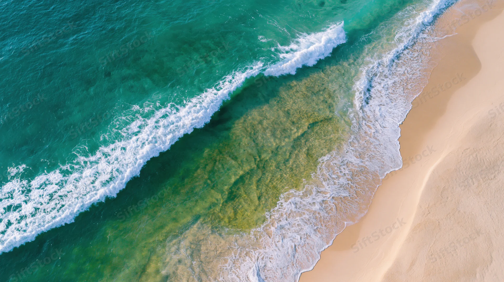 Aerial view of waves breaking on a sandy beach with clear turquoise water
