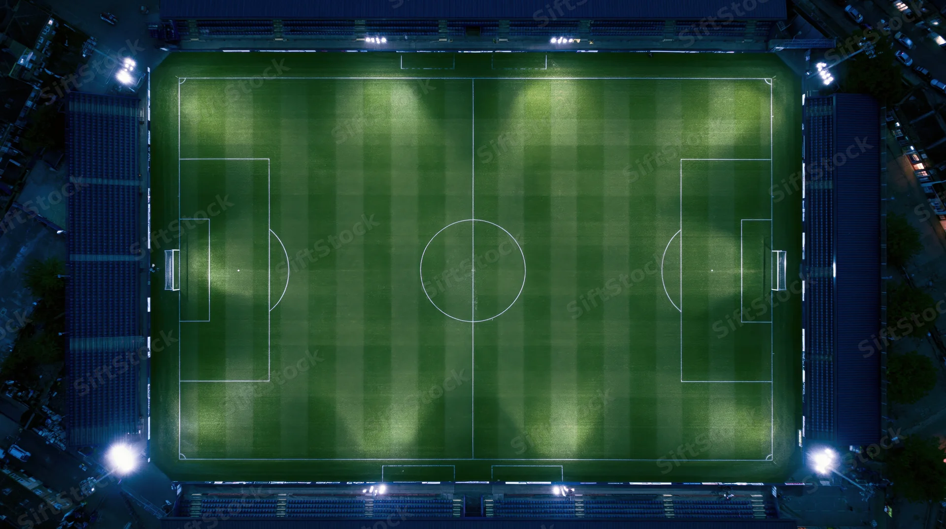Aerial view of a soccer field at night illuminated by floodlights in a stadium