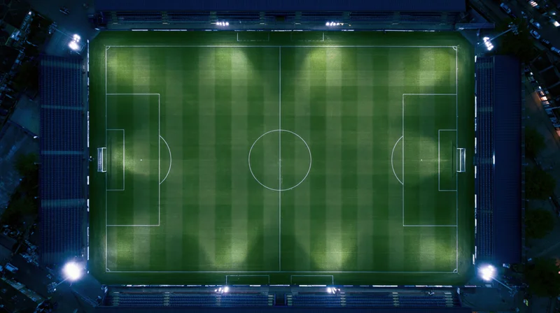 Aerial view of a soccer field at night illuminated by floodlights in a stadium