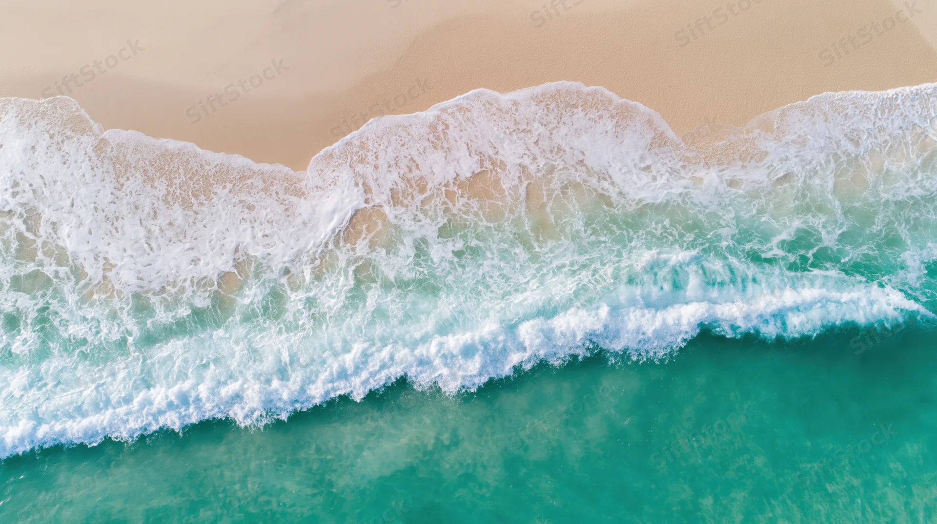 Aerial view of turquoise ocean waves breaking on a sandy tropical beach