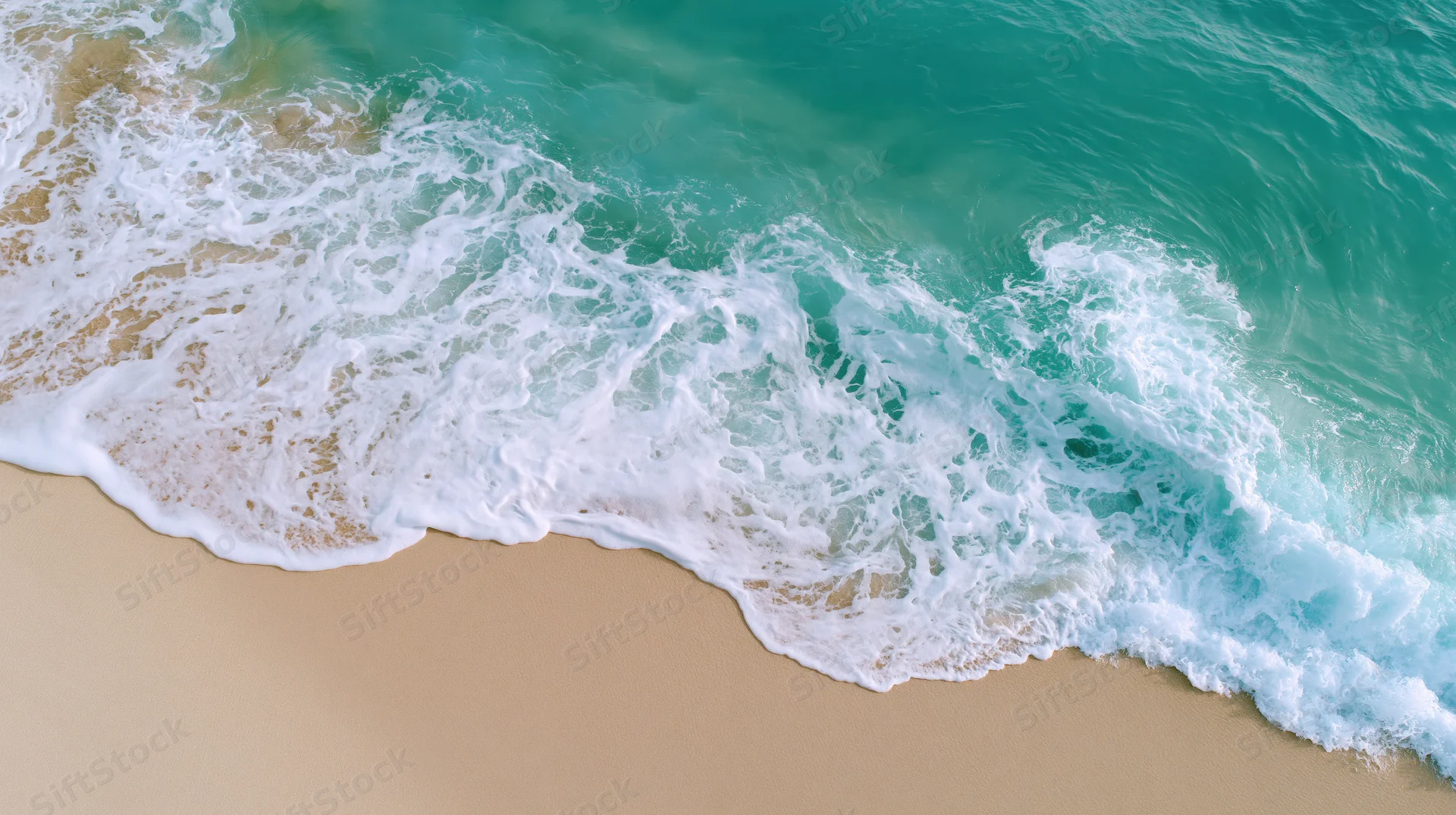 Aerial view of turquoise ocean waves breaking on sandy beach