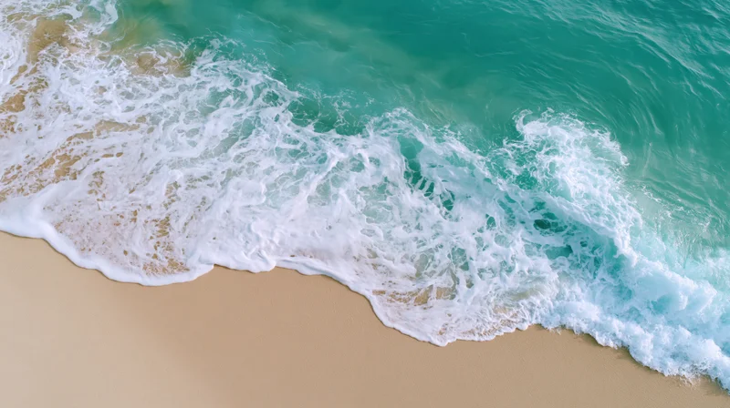 Aerial view of turquoise ocean waves breaking on sandy beach