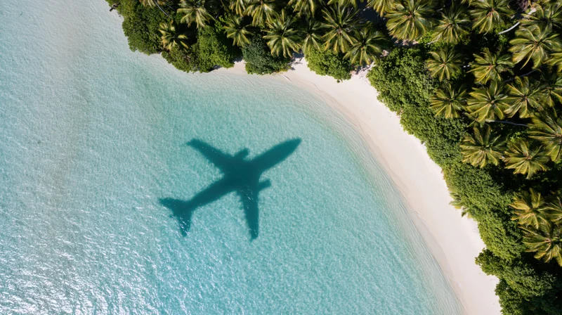 Aerial view of tropical island beach with airplane shadow on turquoise water