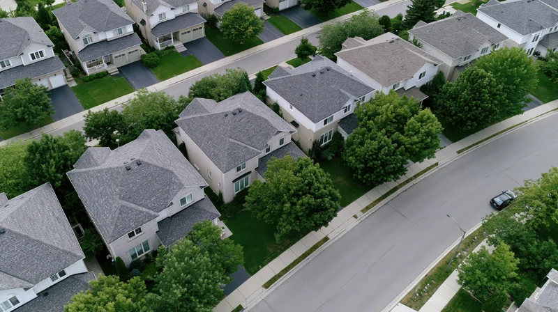 Aerial drone view of suburban neighborhood with houses, trees, and streets from above