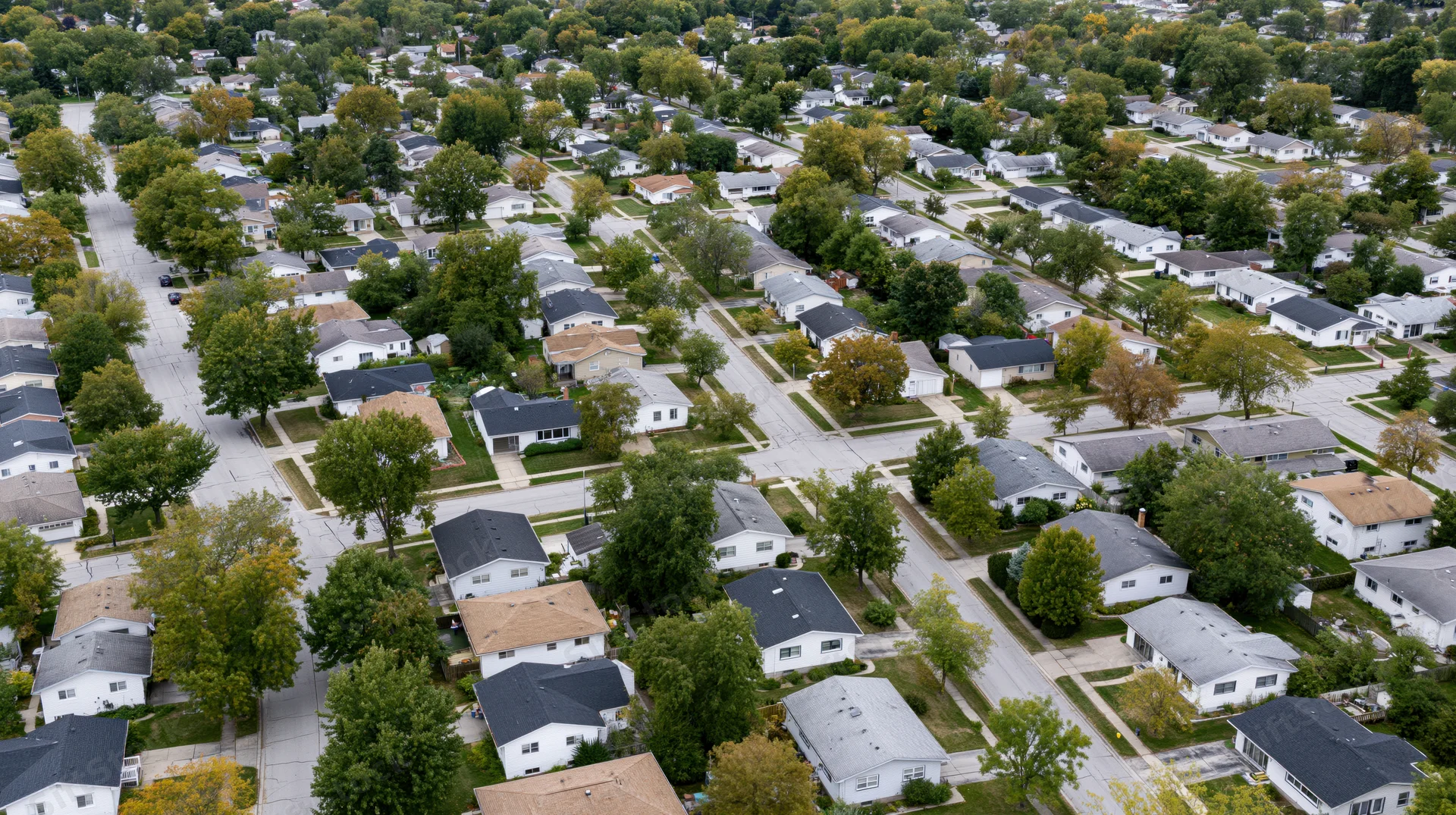 Aerial drone view looking straight down over a quiet midwest suburban neighborhood with houses, trees, and streets