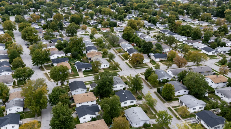 Aerial drone view looking straight down over a quiet midwest suburban neighborhood with houses, trees, and streets
