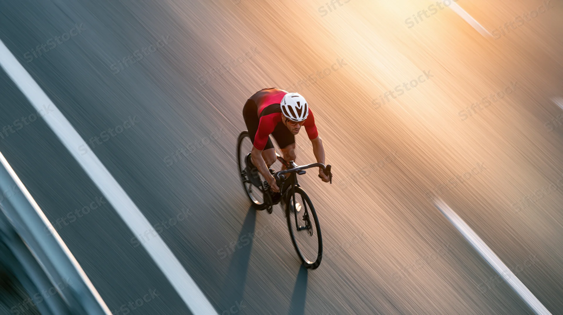 Overhead view of a cyclist sprinting on a road during golden hour