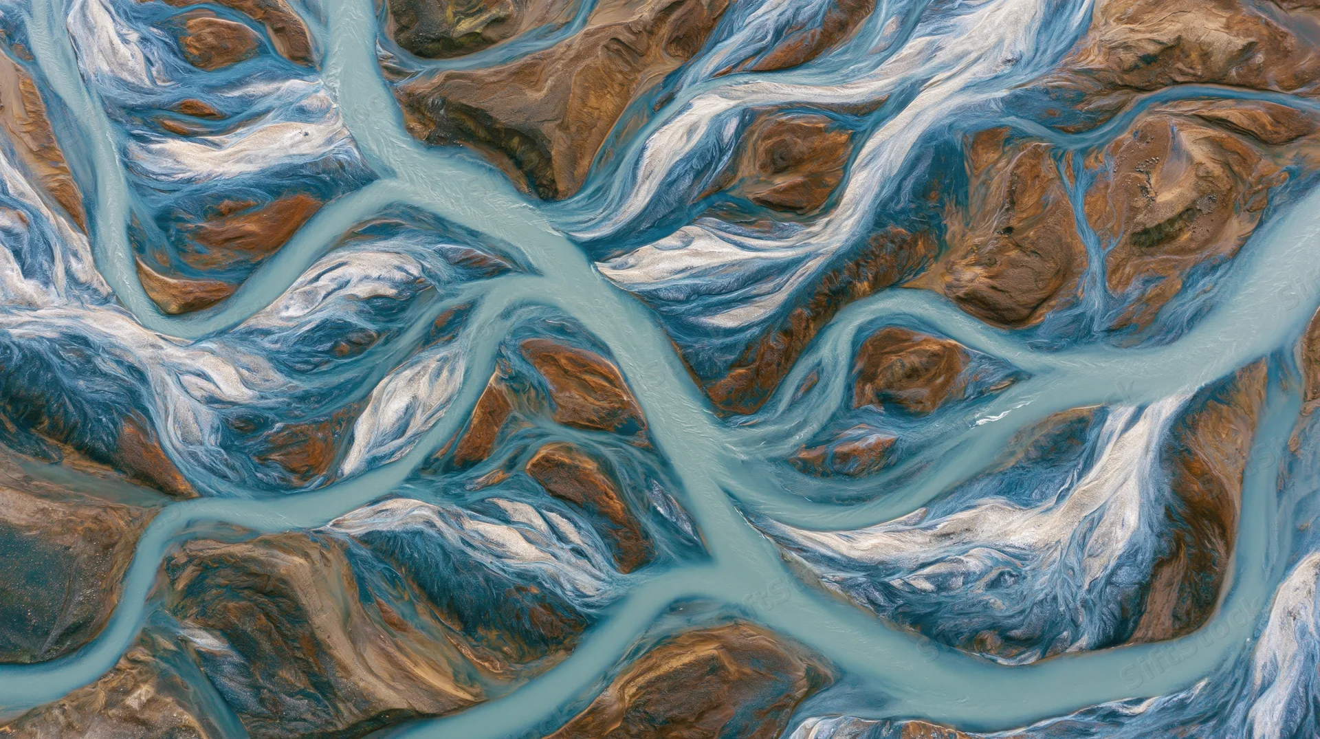 Aerial topdown view of a braided glacial river delta with multiple channels flowing through rocky terrain