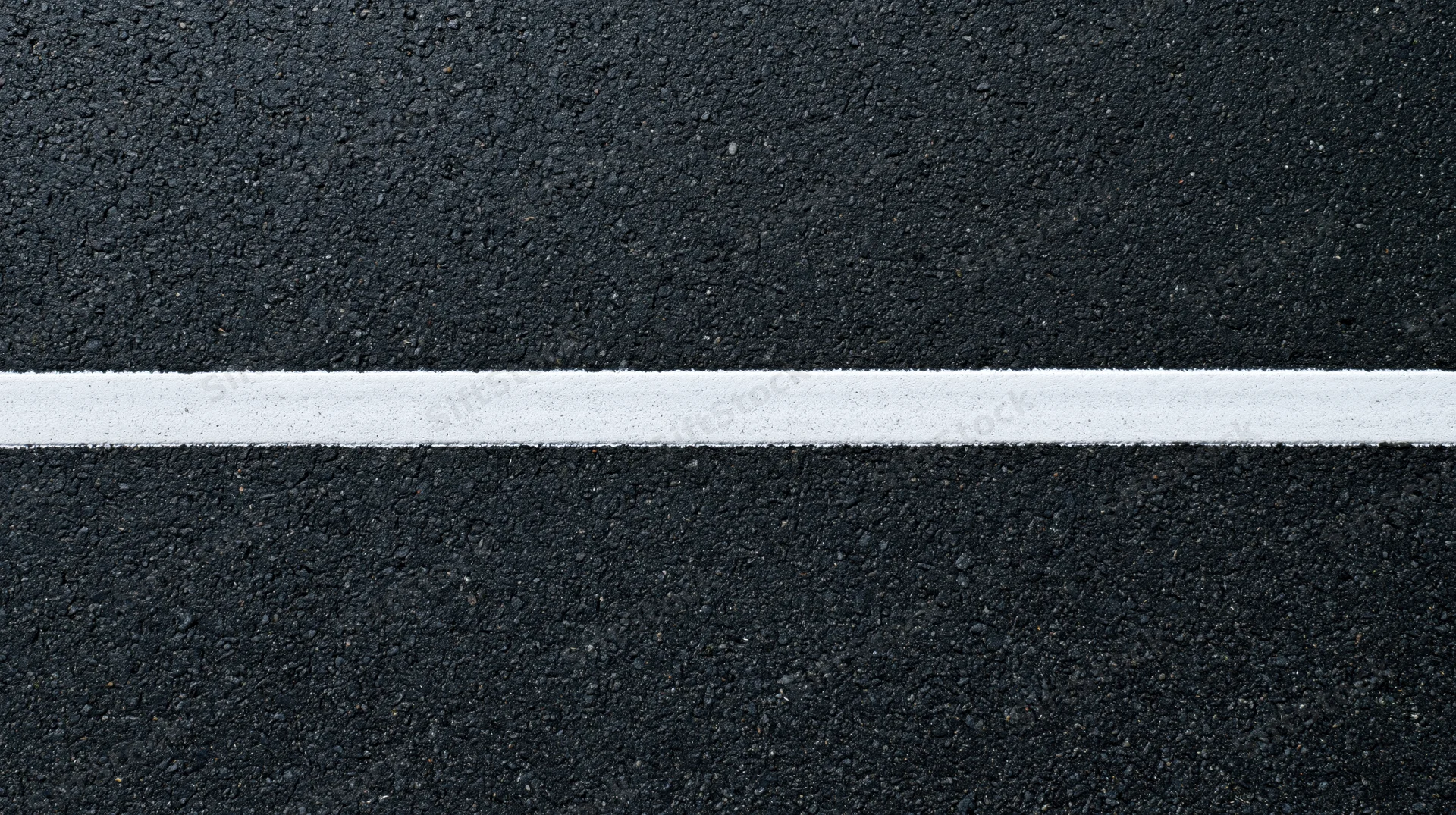 Aerial top-down close-up of dark asphalt road surface with a white painted line running horizontally across the frame