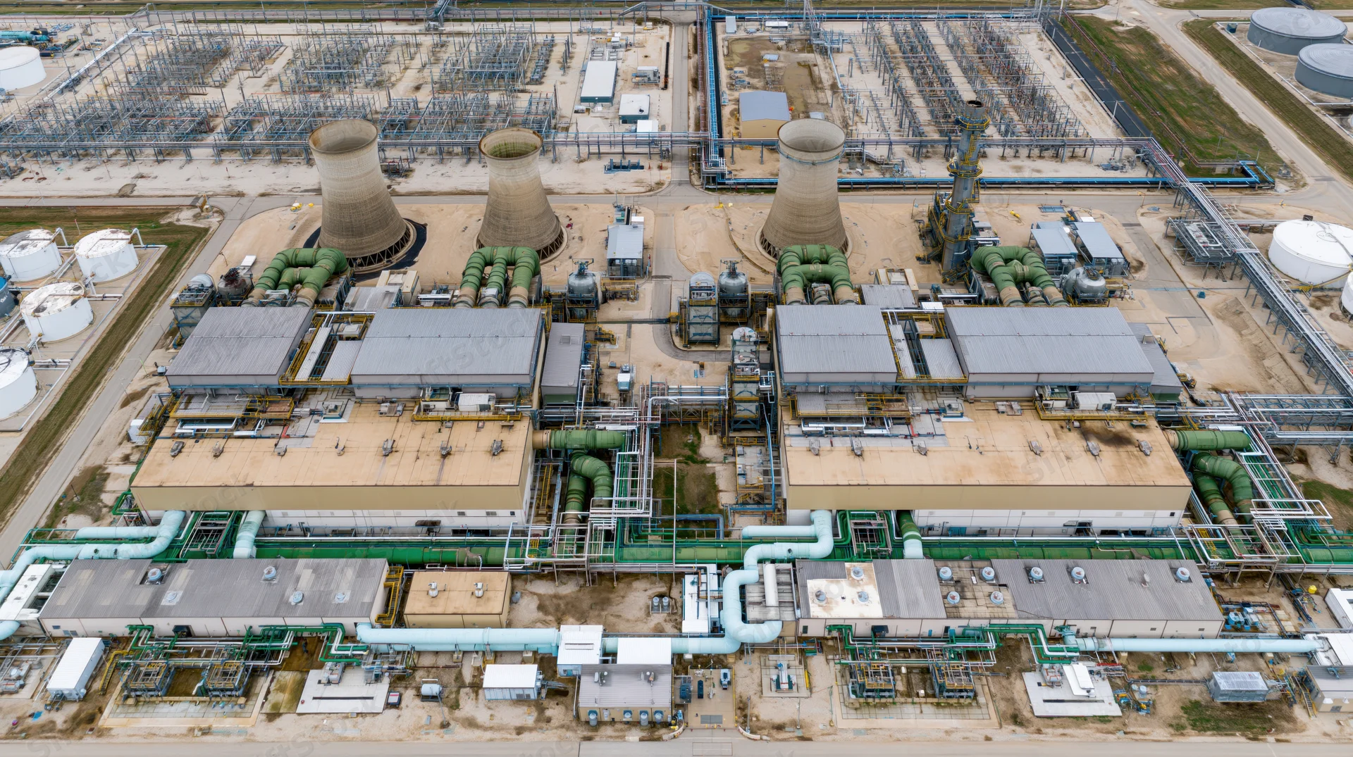 Aerial top-down view of a large industrial power plant with cooling towers and interconnected pipelines