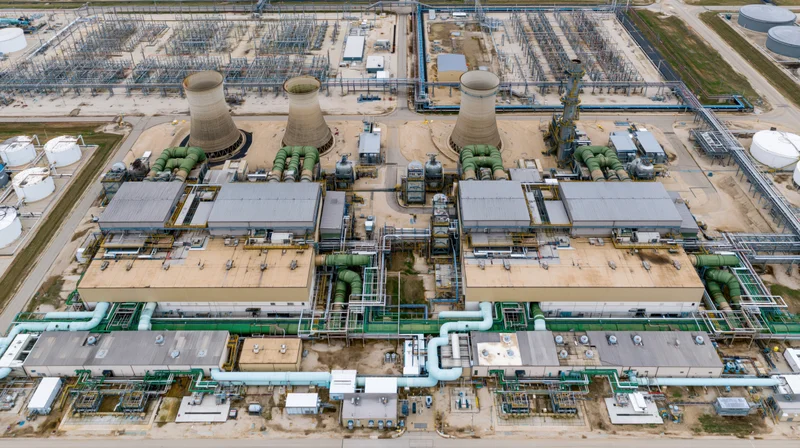 Aerial top-down view of a large industrial power plant with cooling towers and interconnected pipelines
