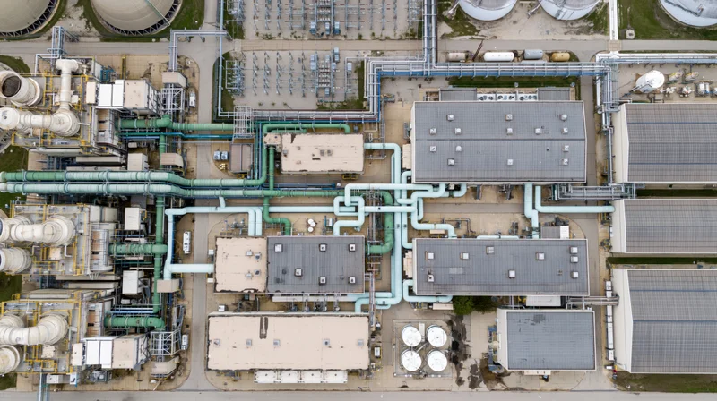 Aerial top-down view of an industrial power plant complex with interconnected pipes and storage tanks