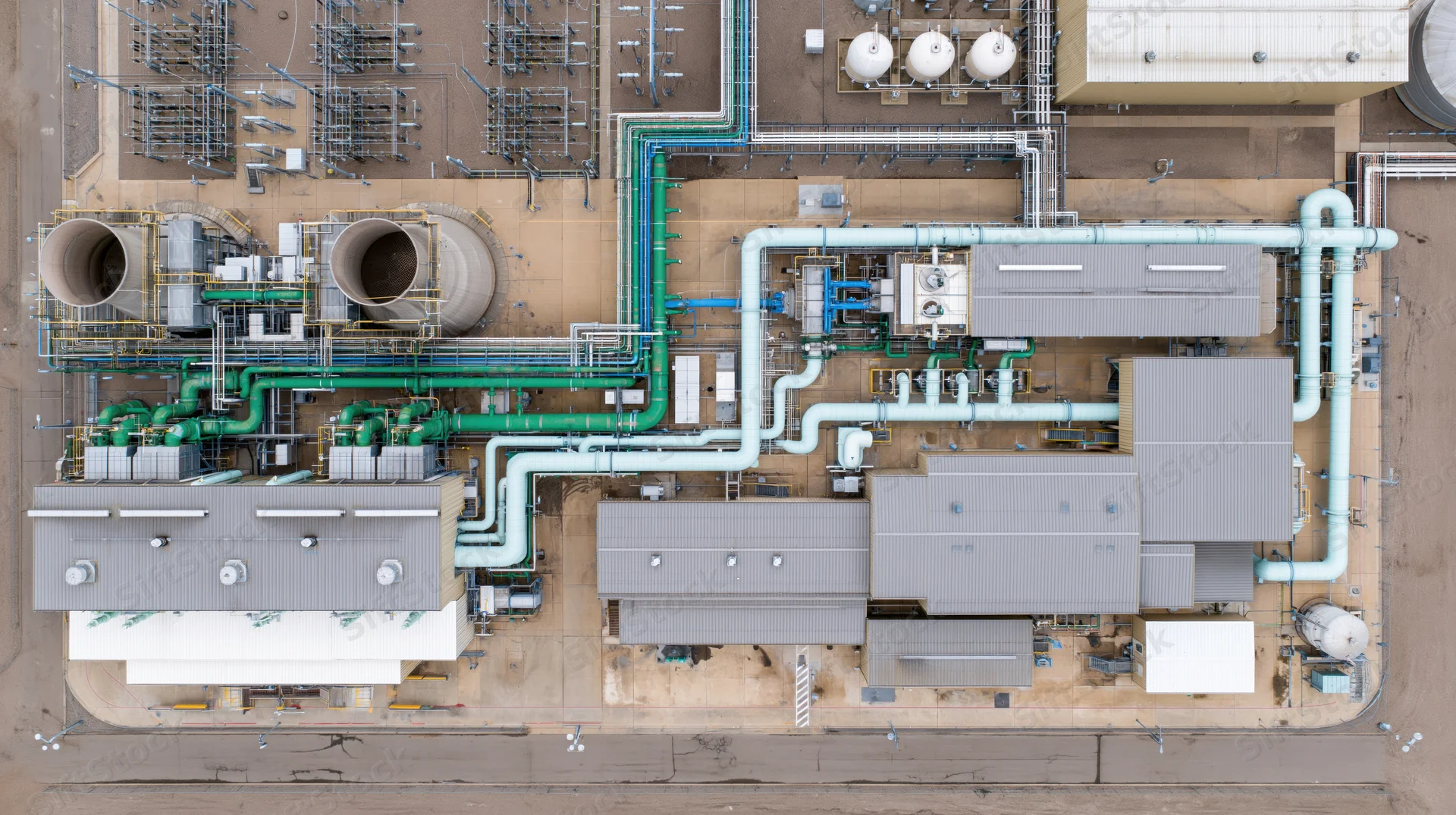 Aerial top-down view of a large industrial power plant with cooling towers and interconnected pipes