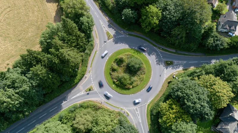 Aerial top-down view of a british roundabout with cars navigating the circular road intersection surrounded by greenery and residential houses