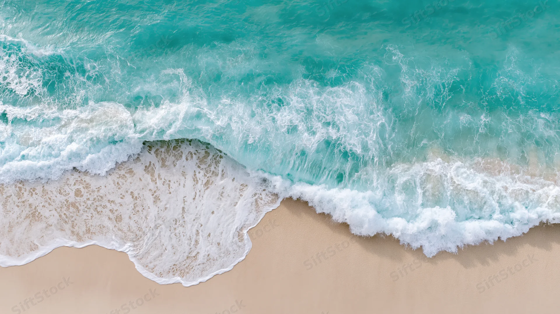 Aerial top-down view of gentle ocean wave breaking on sandy beach