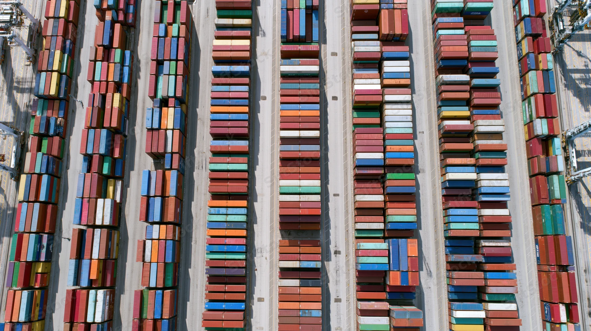 Aerial top-down view of rows of stacked shipping containers in a commercial port