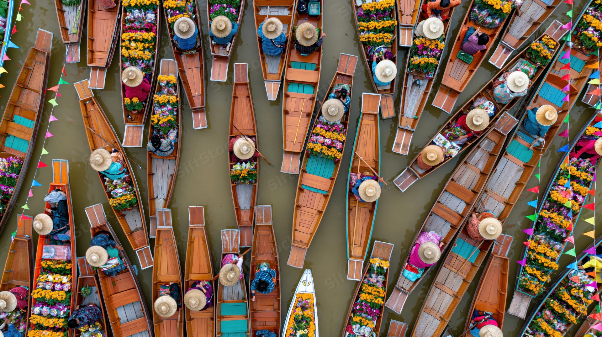 Aerial top-down view of wooden boats filled with flowers and vendors at a crowded thai floating market