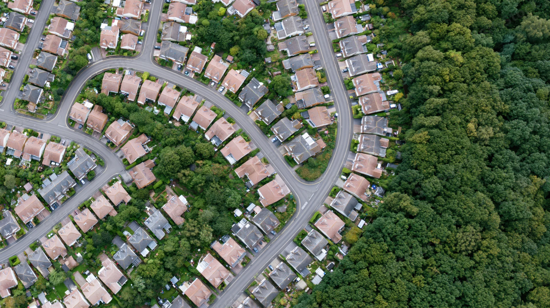 Aerial top-down view of a dense british residential suburb with winding streets and greenery