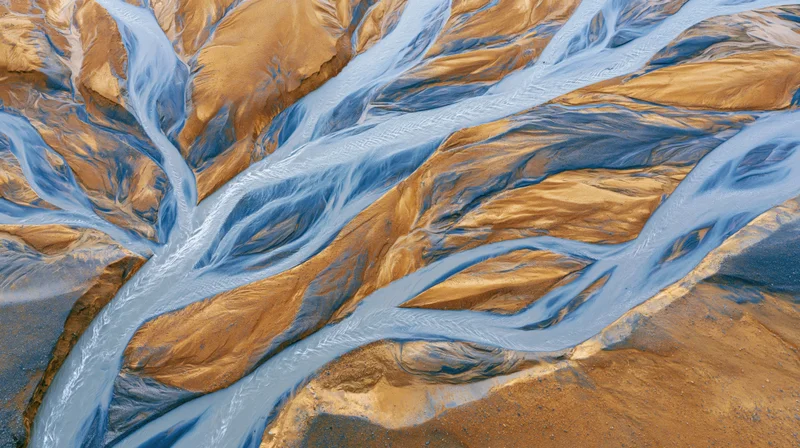 Aerial top-down view of a glacial braided river delta flowing through icy terrain in iceland