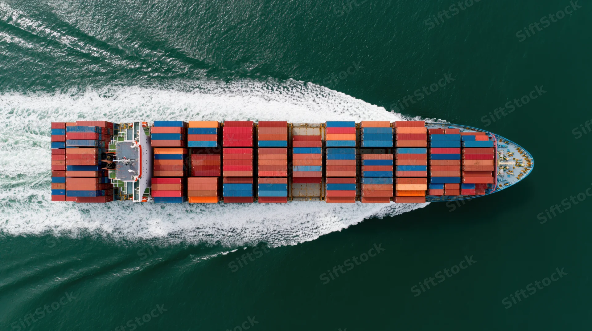 Large cargo container ship moving across ocean leaving white wake