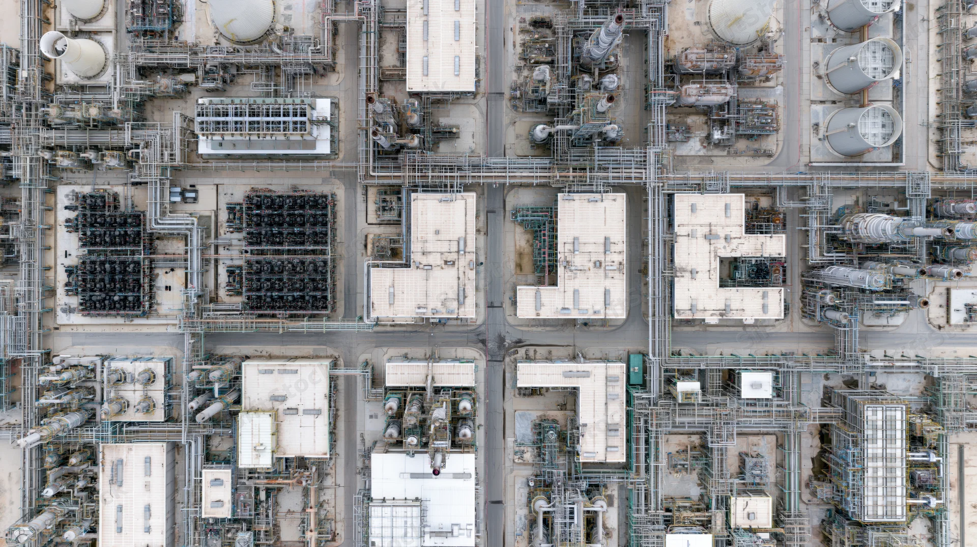 Aerial top-down view of a large petrochemical plant with interconnected tanks, pipelines and processing units