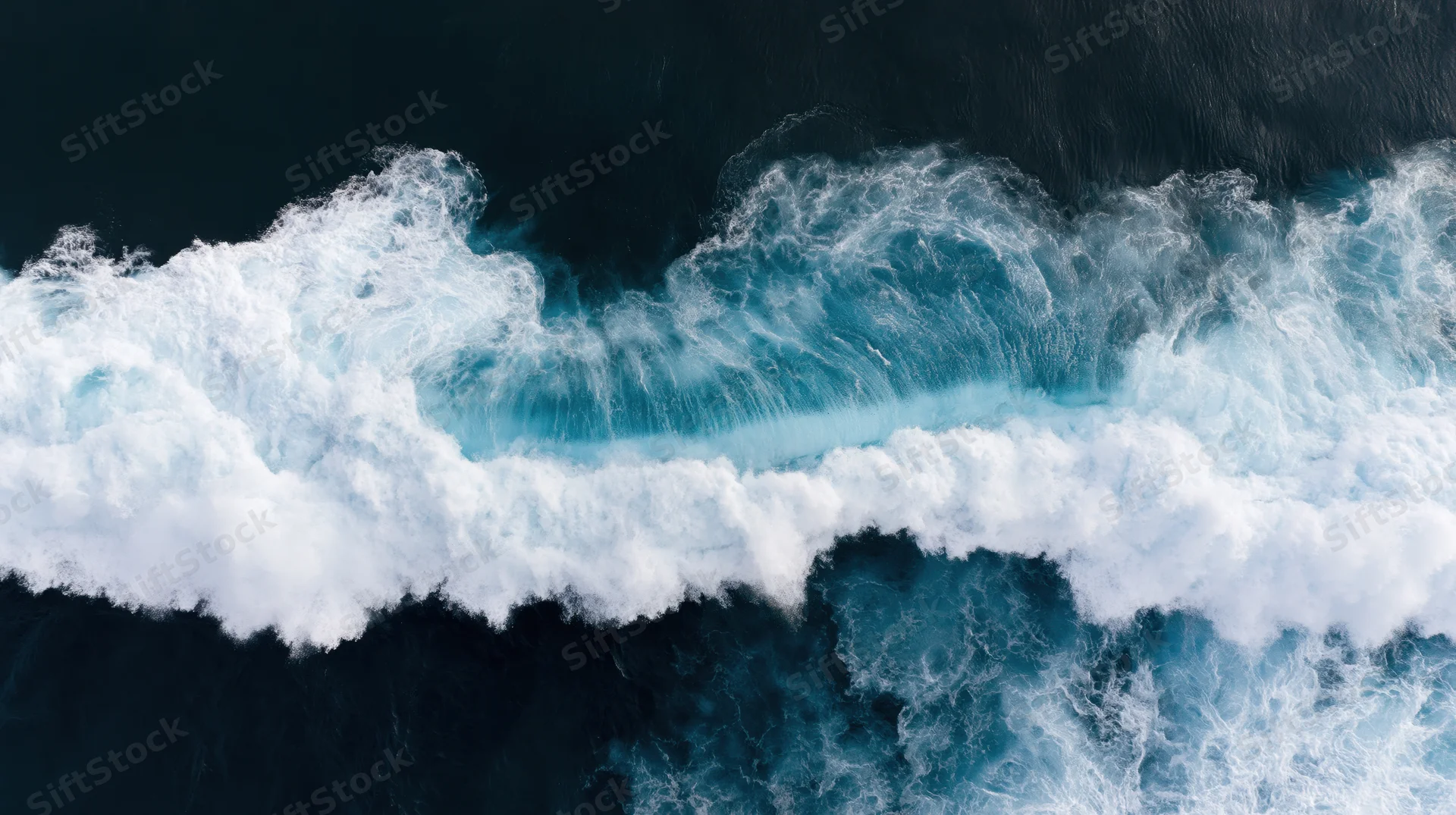 Aerial top-down view of a large ocean wave breaking with white foam and dark blue water