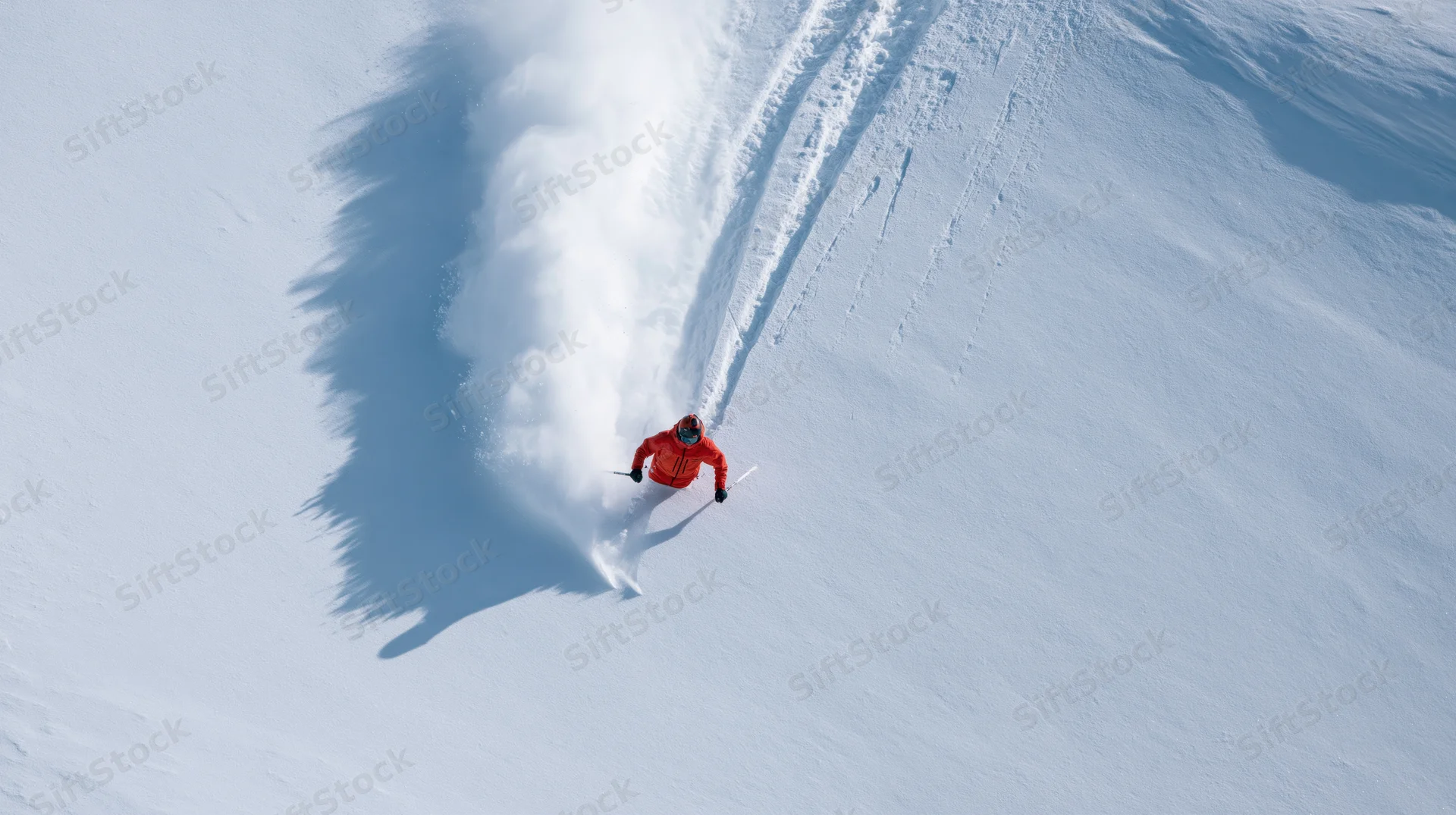 Skier carving through deep powder snow on a mountain slope from an aerial top-down view