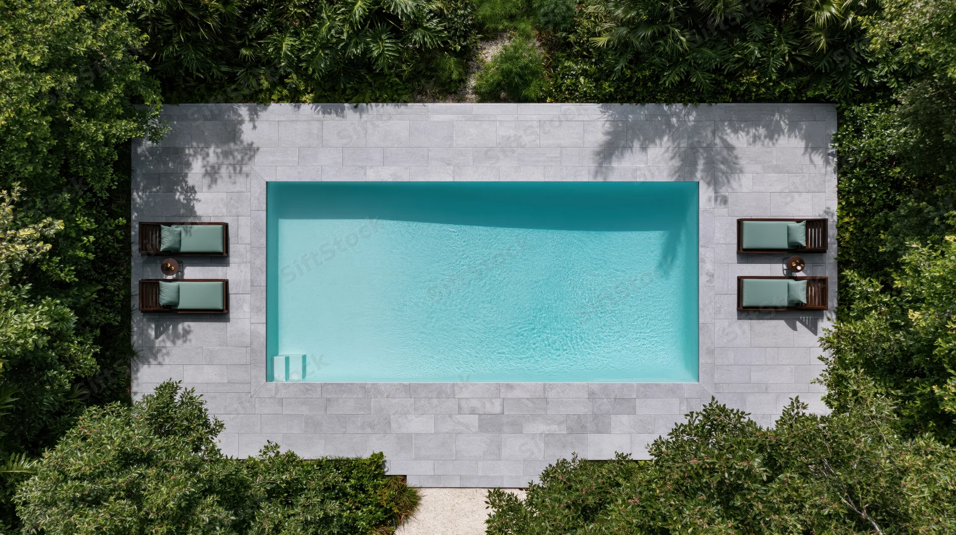Aerial top-down view of a rectangular outdoor swimming pool surrounded by green trees and stone deck with lounge chairs