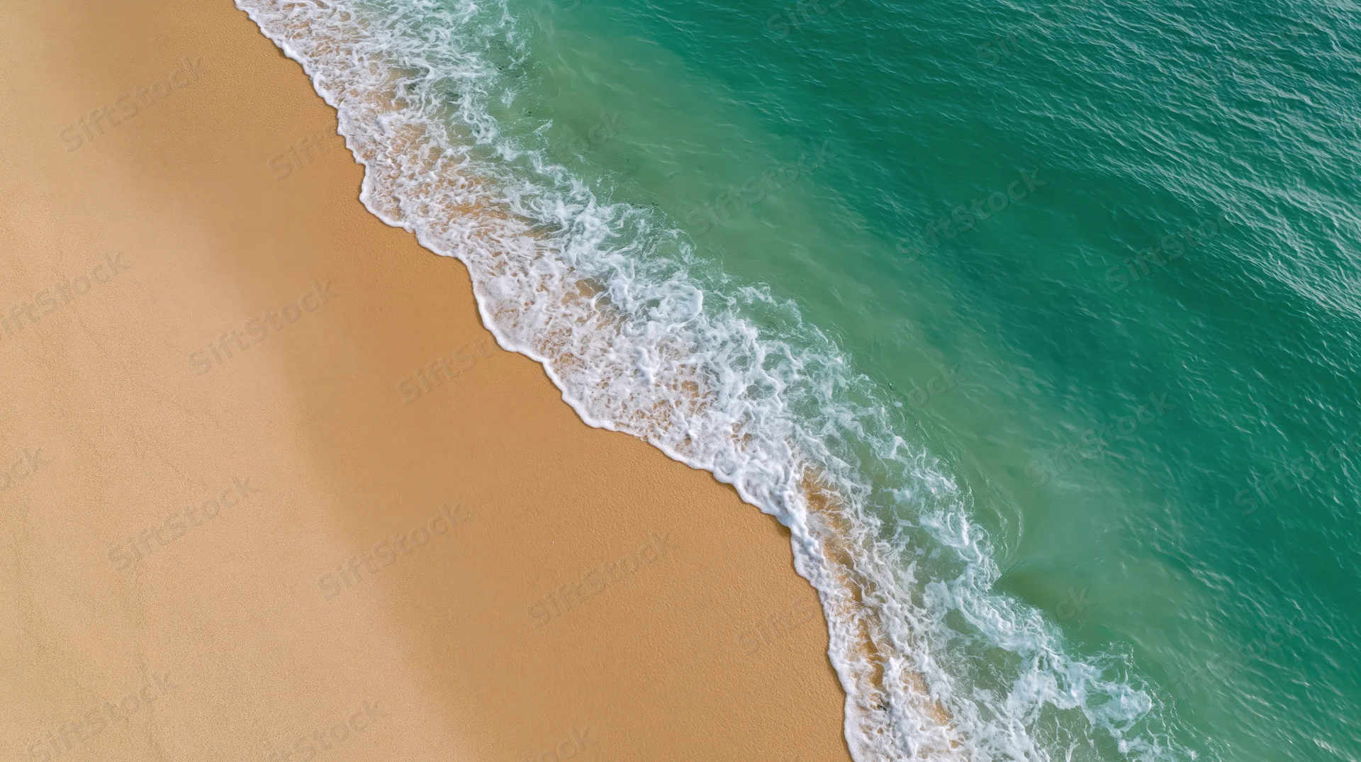 Aerial top-down view of waves meeting sandy beach shoreline
