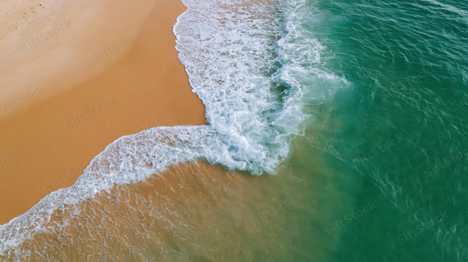 Aerial top-down view of waves breaking on a sandy beach shoreline