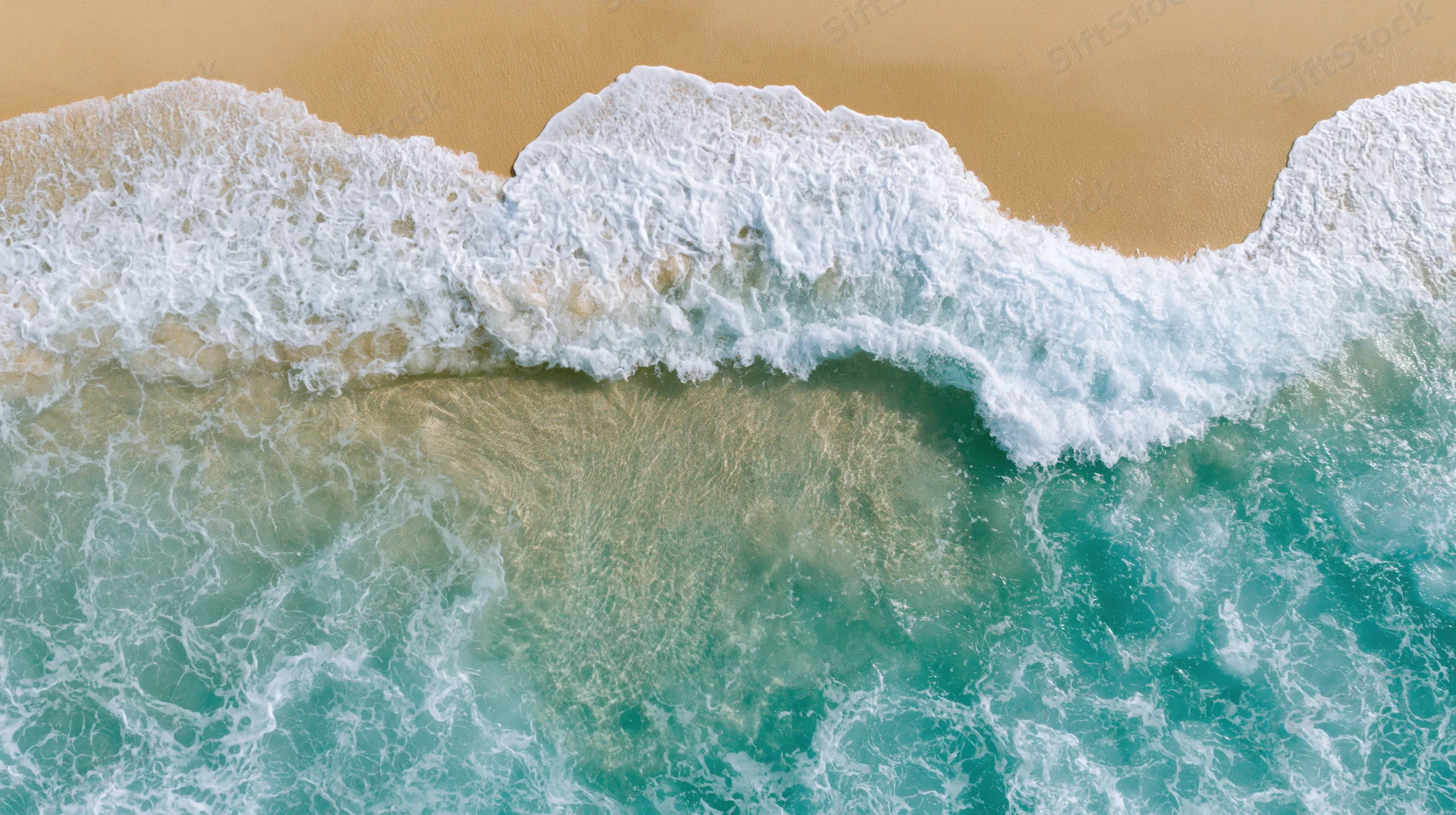 Aerial top-down view of waves breaking on a sandy tropical shoreline