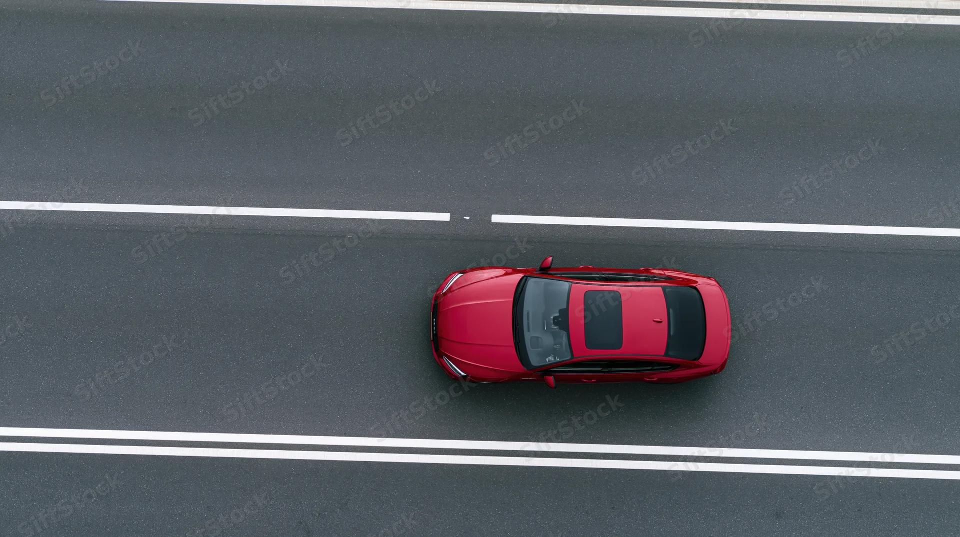 Red sedan driving alone on a highway viewed from above