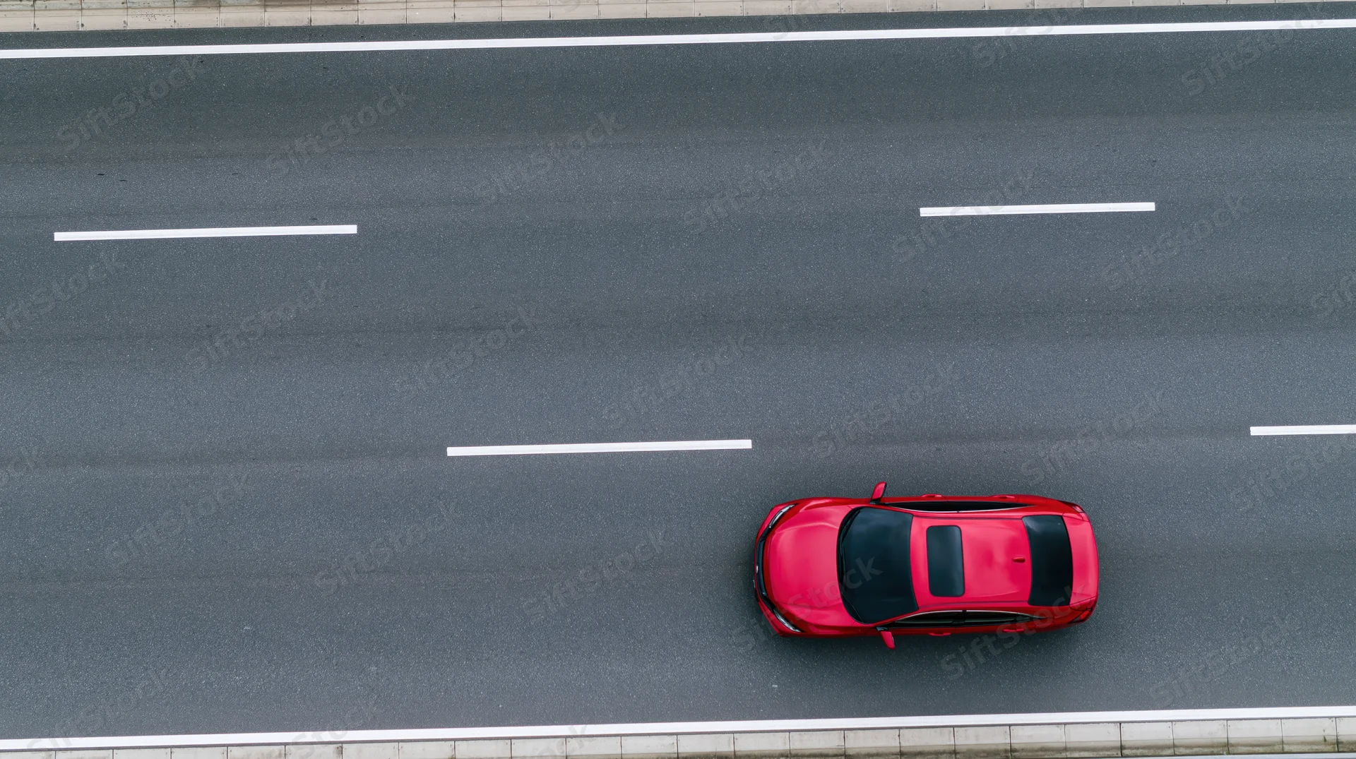 Red sedan driving alone on a multi-lane highway viewed from above