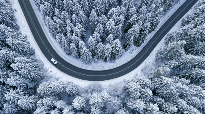 Aerial view of winding two-lane road through snow forest