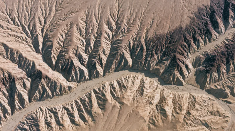 Aerial top-down view of an arid desert canyon system with braided erosion patterns and deep ravines