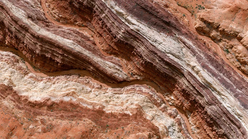 Aerial top-down view of eroded desert canyon with layered sedimentary rock formations