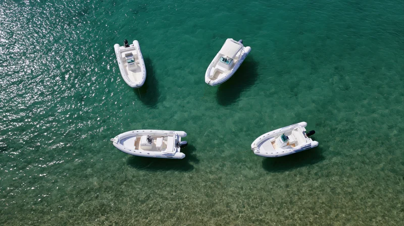 Four small motorboats anchored in clear turquoise water viewed from above