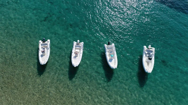 Four small motorboats anchored in clear turquoise water viewed from above