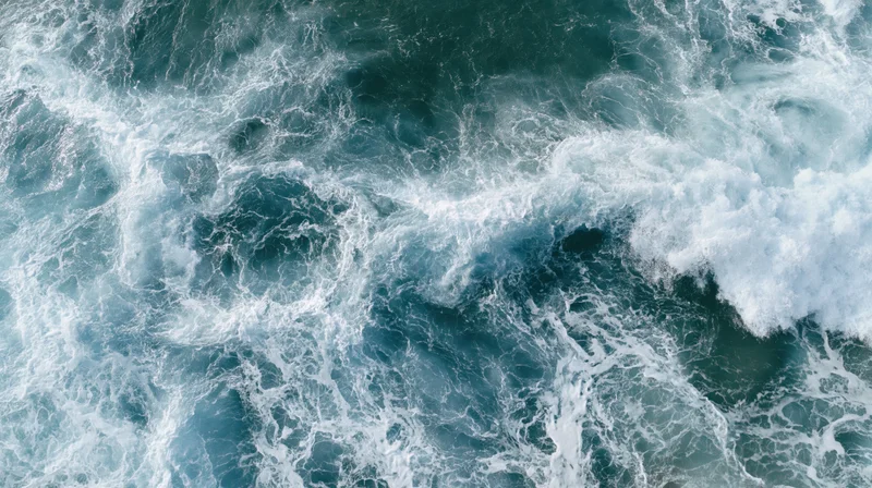 Aerial top-down view of ocean waves breaking and churning with white foam on the surface