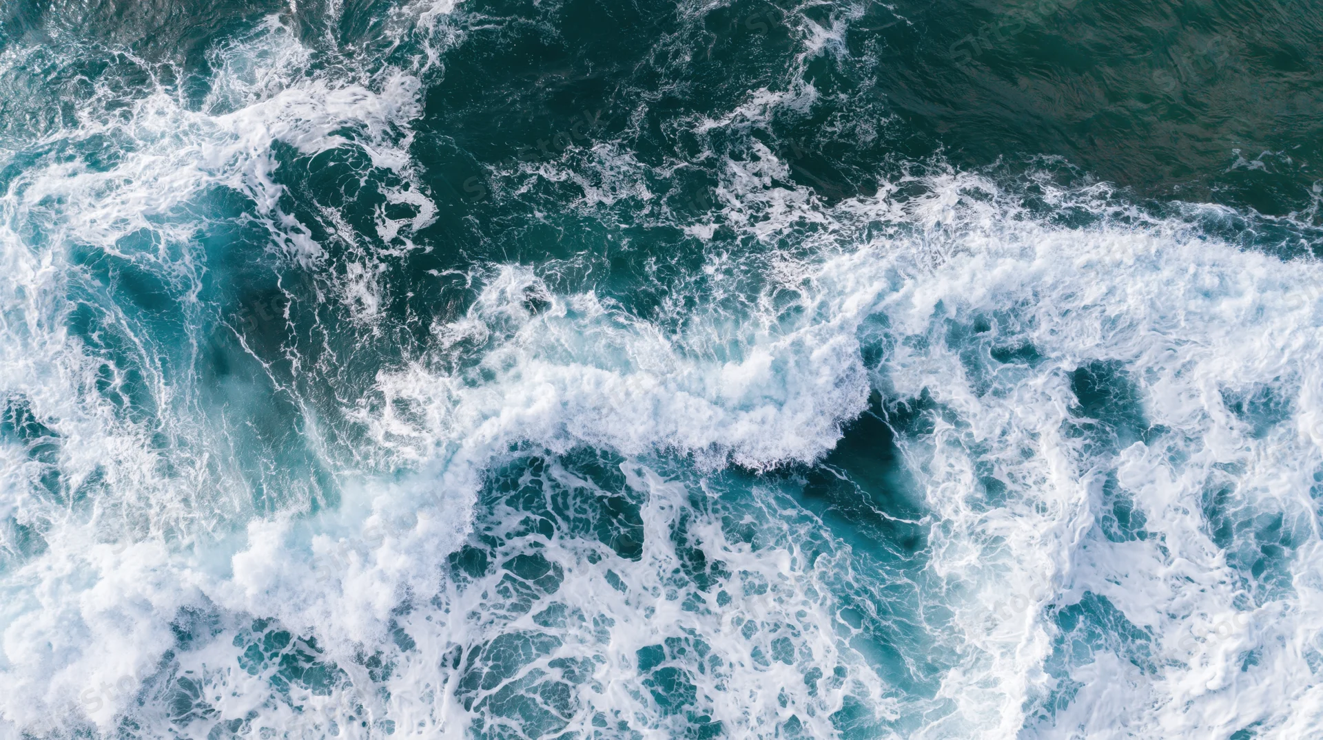 Aerial top-down view of ocean waves breaking and churning with white foam on blue water surface