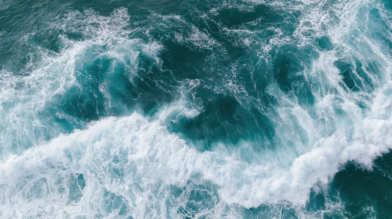 Aerial top-down view of ocean waves breaking and churning with white foam and turquoise water