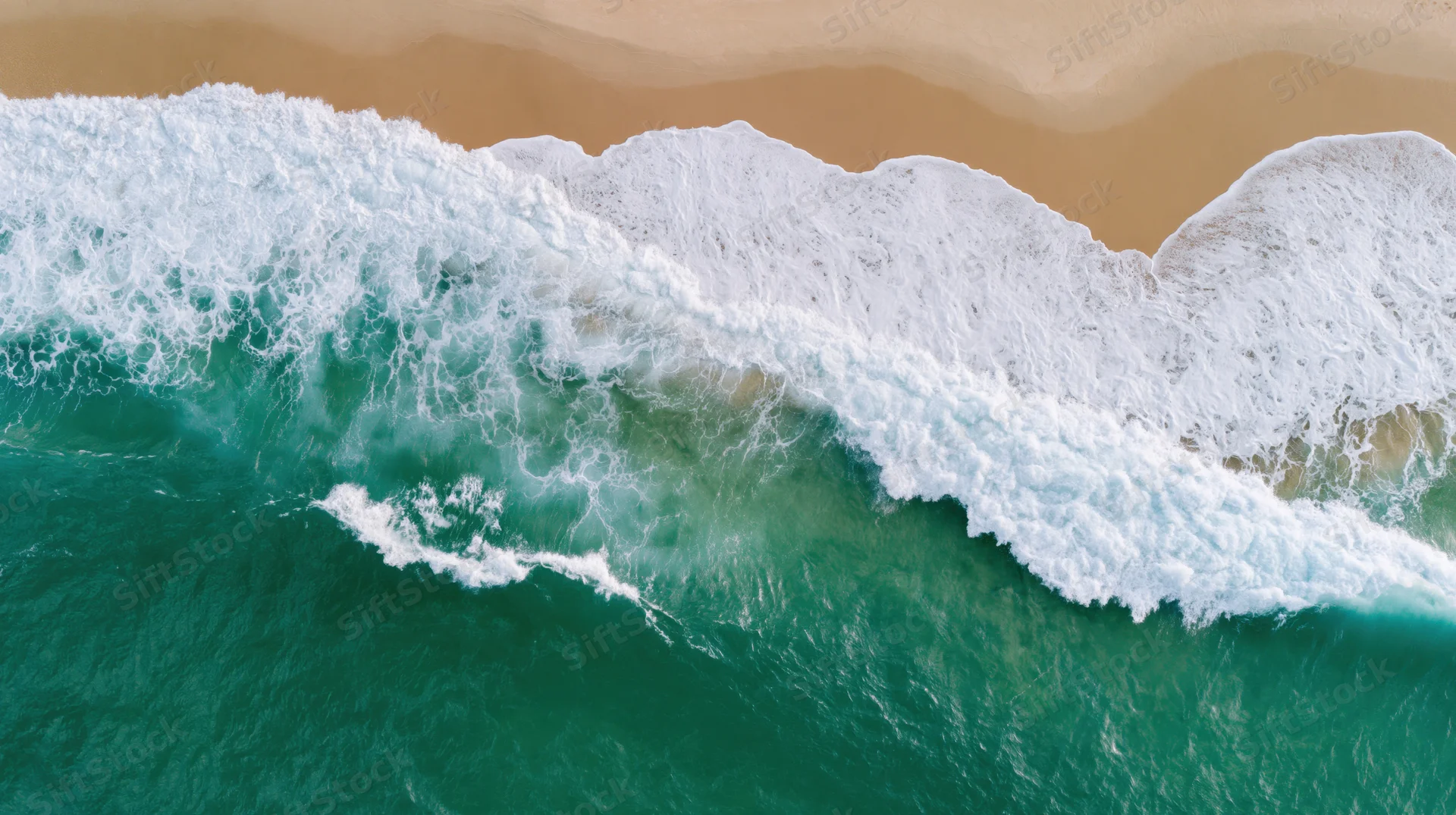 Aerial top-down view of ocean waves breaking onto sandy beach