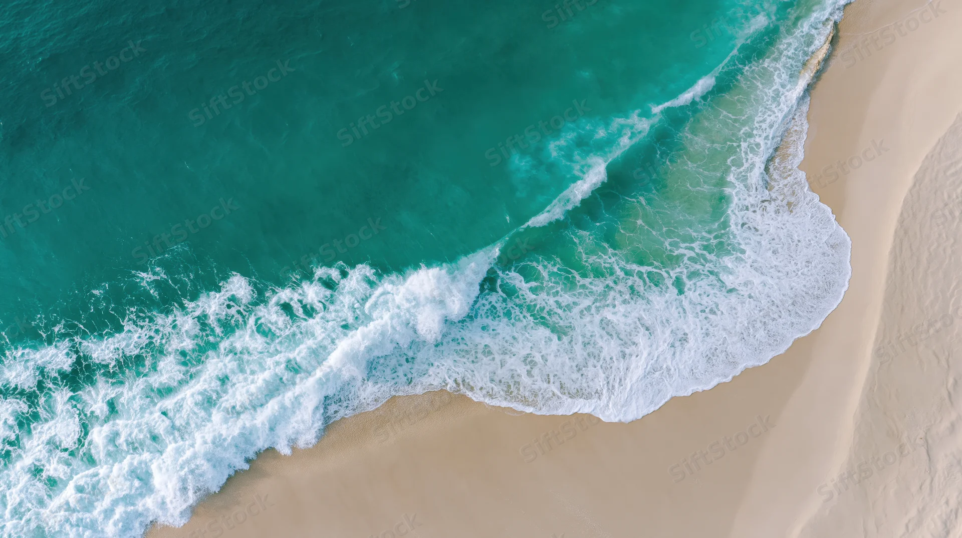 Aerial top-down view of ocean waves breaking onto a wide sandy beach