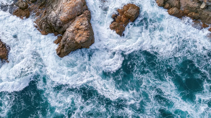 Aerial top-down view of ocean waves crashing against rocky coastline