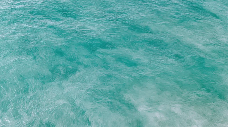 Aerial top-down view of open ocean surface with gentle ripple