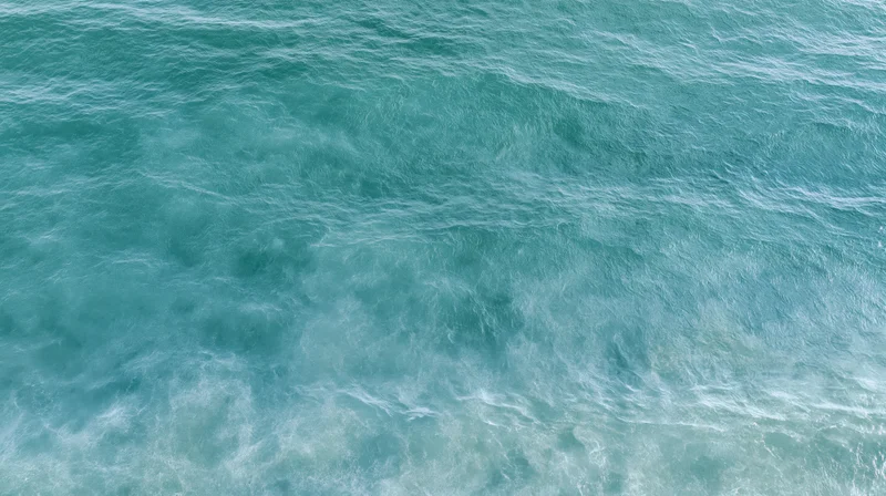 Aerial top-down view of open ocean surface with gentle ripple